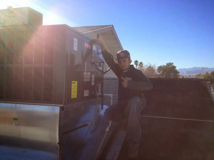 HVAC technician performing AC Tune-Up on a rooftop unit in Mecca